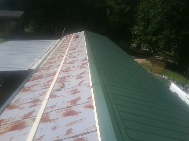 Old rusted panels beside newly installed green metal roofing — Wind Damage Roof Repair by Roofing Brothers in Highland Park