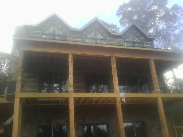 Dormers and porch framing on a large log home under construction — Roof Coating work by our crew in Highland Park