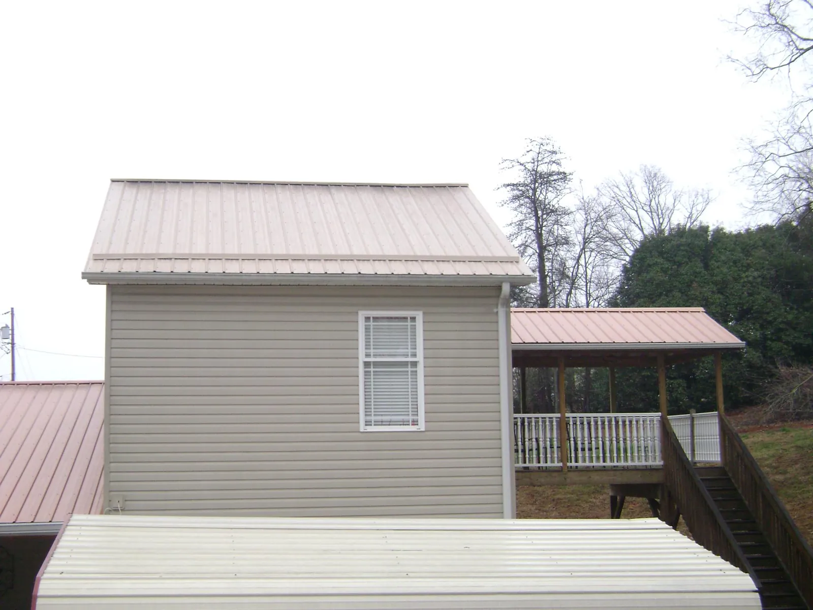 Tan metal roofs on a two story addition and attached porch, from a Roof Replacement job in Highland Park